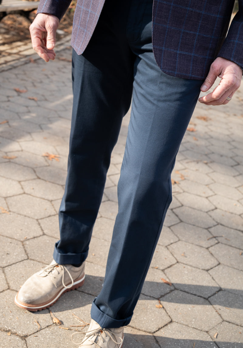 Person wearing navy pants and beige shoes on a paved surface